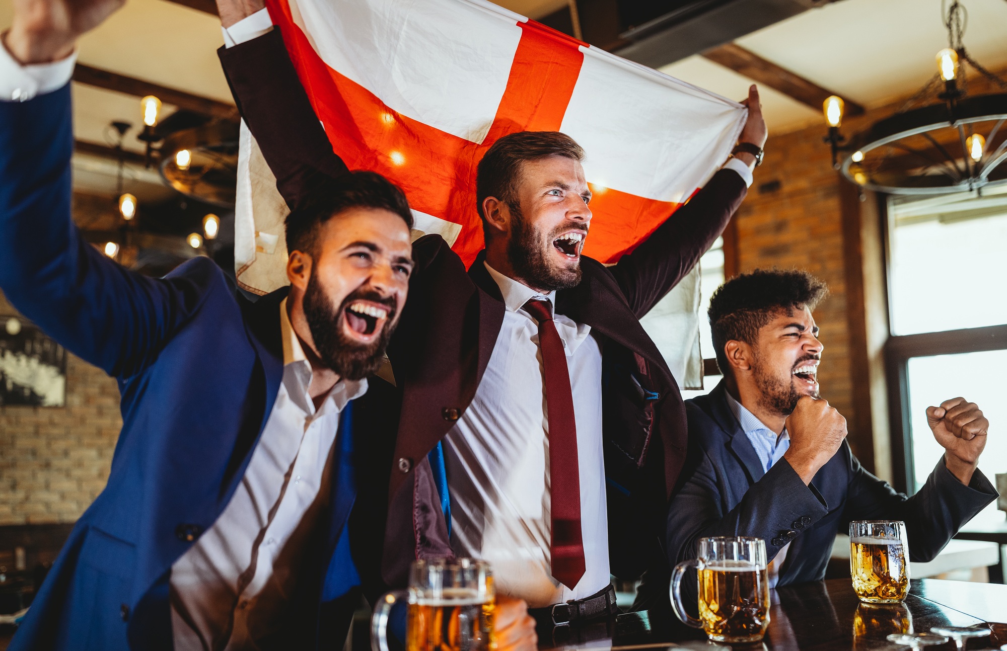 Business men in pub cheering for a sporting event