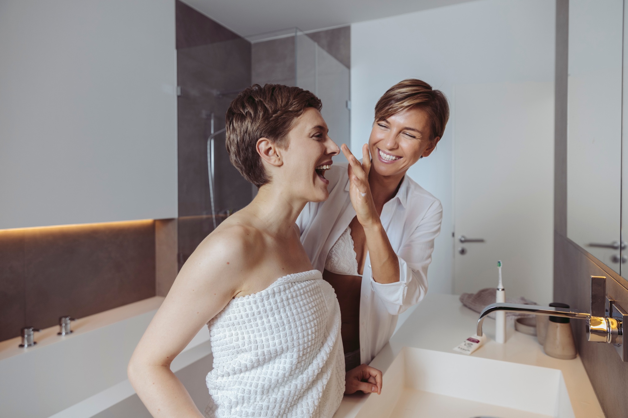 Happy lesbian couple getting ready for their day in the bathroom